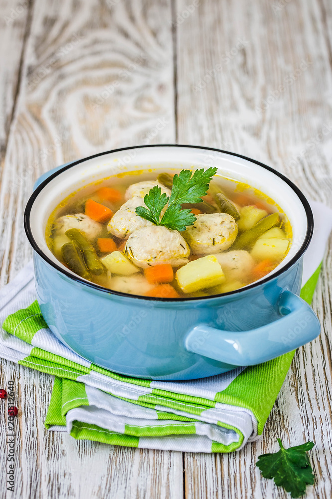 Cheesy parmesan meatball soup in a pot on white rustic background. Selective focus, space for text. Cheesy parmesan meatball soup in a pot on white rustic background. Selective focus, space for text.