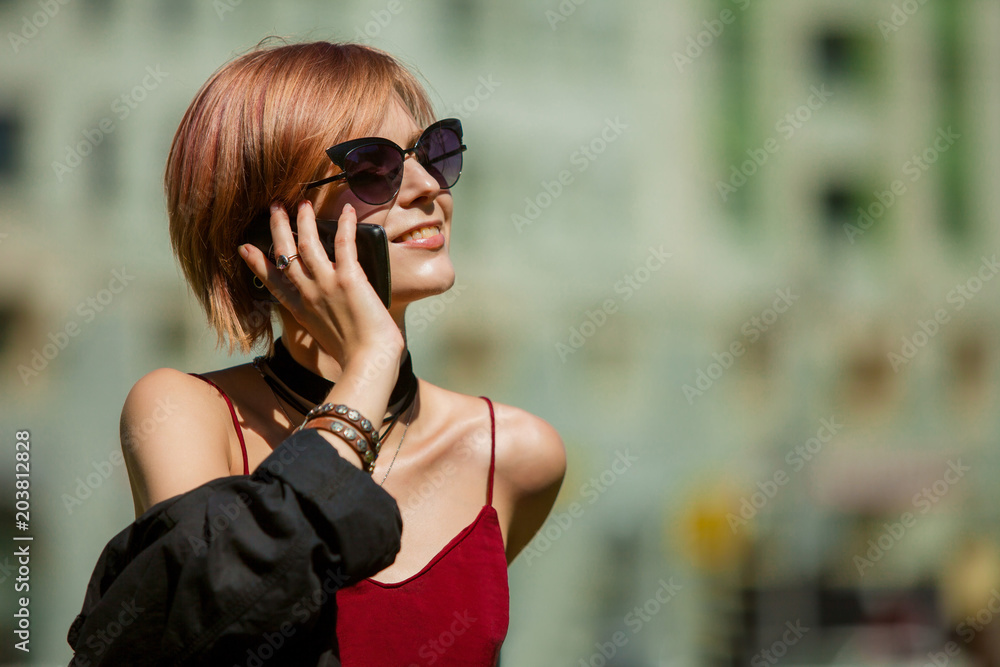 Portrait of a beautiful young girl talking on a mobile phone in a city street. Portrait of a beautiful young girl talking on a mobile phone in a city street.