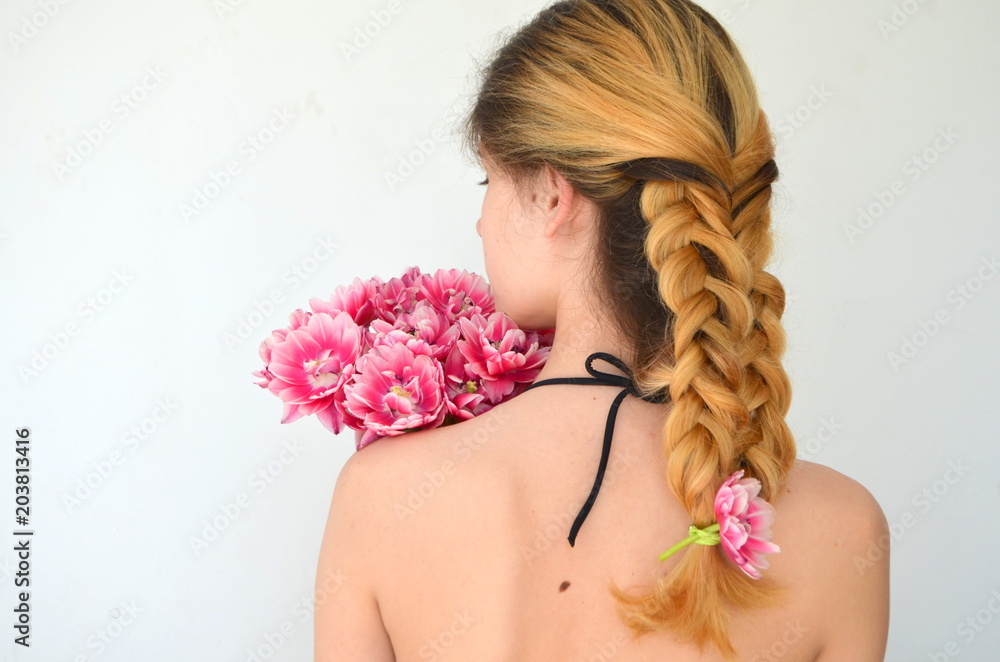 Девушка с красивой прической Волосы плетеные из пяти прядей. Красивый розовый тюльпан