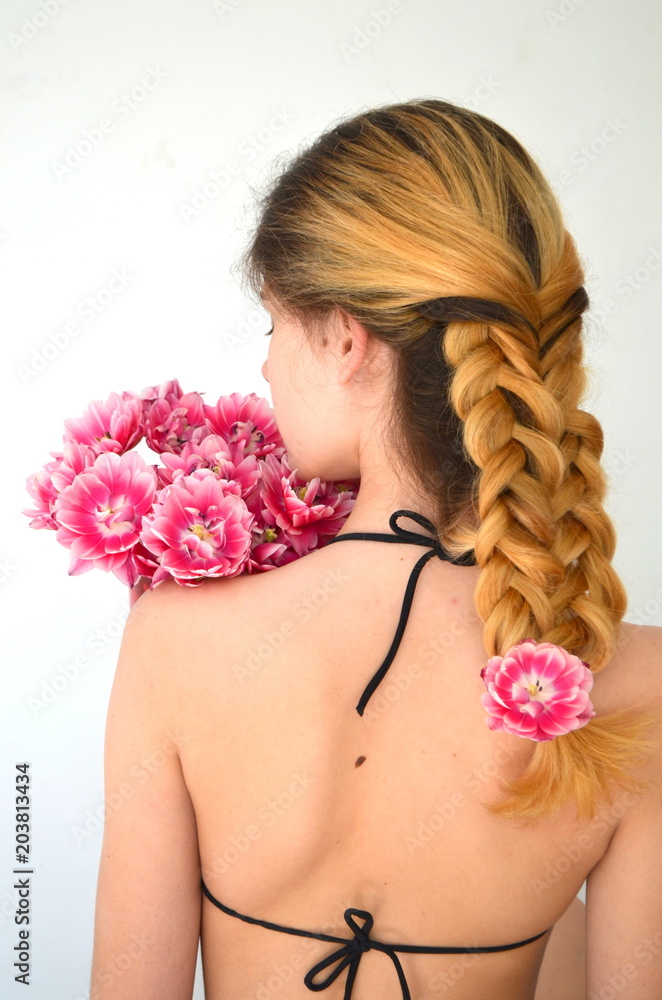 Девушка с красивой прической Волосы плетеные из пяти прядей. Красивый розовый тюльпан