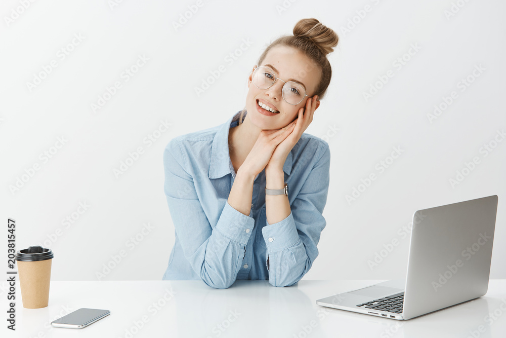 Dreamy good-looking european female in stylish glasses sitting in office near laptop and smartphone, drinking coffee, working on project, smiling broadly at camera, imaging vacation with boyfriend Dreamy good-looking european female in stylish glasses sitting in office near laptop and smartphone, drinking coffee, working on project, smiling broadly at camera, imaging vacation with boyfriend
