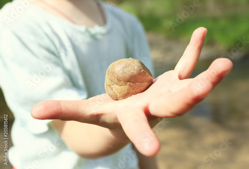 little girl holding a stone in her hand. The stone is a close-up. The girl does not focus