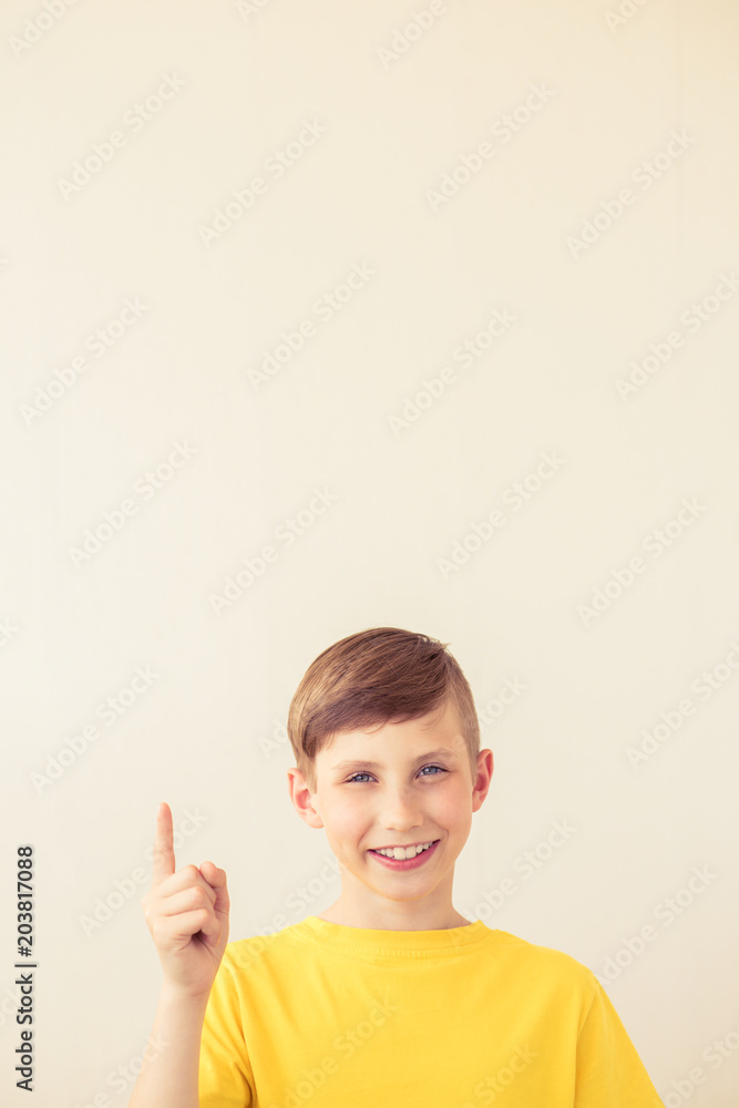 Handsome young teen boy points finger up. Copy space