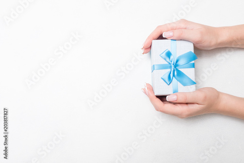 small present with blue ribbon bow in woman hands on white background. Sweet reward gift for holiday or birthday. free space concept