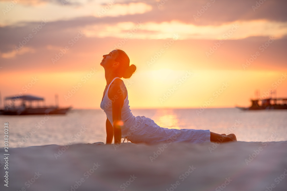 A woman is doing yoga exercises at the sunset on Boracay island, Philippines