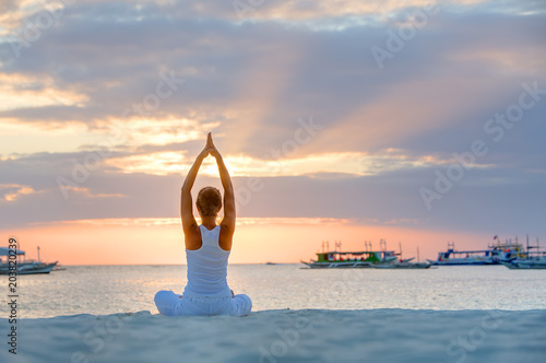 A woman is doing yoga exercises at the sunset on Boracay island, Philippines