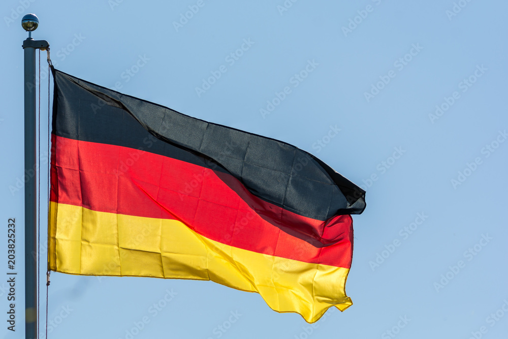 Im Wind wehende Flagge der Bundesrepublik Deutschland vor blauem Himmel Im Wind wehende Flagge der Bundesrepublik Deutschland vor blauem Himmel