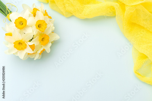Fototapeta Naklejka Na Ścianę i Meble -  Daffodil bouquet with yellow textile decoration on blue pastel background with copy space.