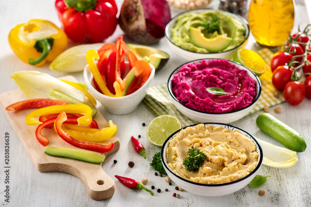 Colorful hummus with vegetables, vegan snack, beetroot and avocado hummus, vegetarian eating Colorful hummus with vegetables, vegan snack, beetroot and avocado hummus, vegetarian eating