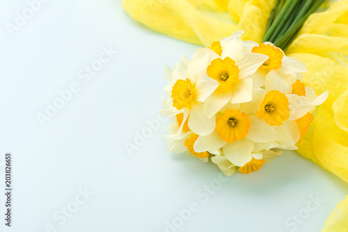 Fototapeta Naklejka Na Ścianę i Meble -  Daffodil bouquet with yellow textile decoration on blue pastel background with copy space.