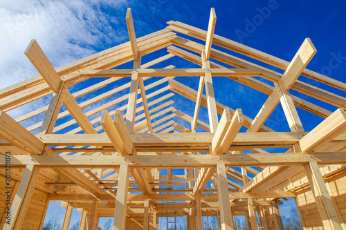 A frame of a house against a blue sky. The frame of the cottage. The beginning of the construction of the house. Construction site.