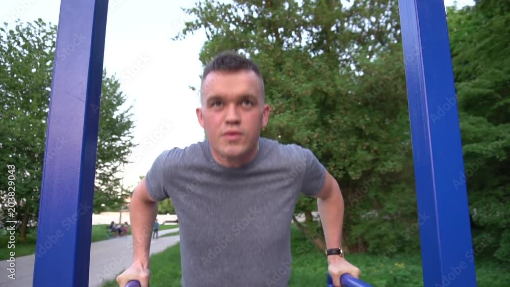 Professional male gymnast training on parallel bars outdoor. Professional male gymnast training on parallel bars outdoor.