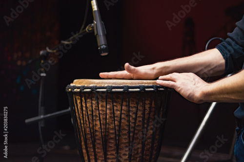 African drum, microphone studio recording, drummer beats the drum with his hands movement