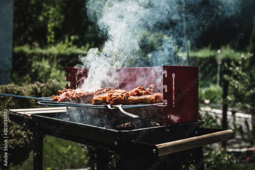 Grill view with chickens. Chickens and sausages are fried on the grill. Spending time together with the family at the grill. Social meetings, friends. Red gril with kindling and coal. Grill view with chickens. Chickens and sausages are fried on the grill. Spending time together with the family at the grill. Social meetings, friends. Red gril with kindling and coal.