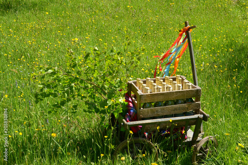 A handcart with a blanket, a beer box, colorful ribbons on a wonderful spring meadow for fathers day