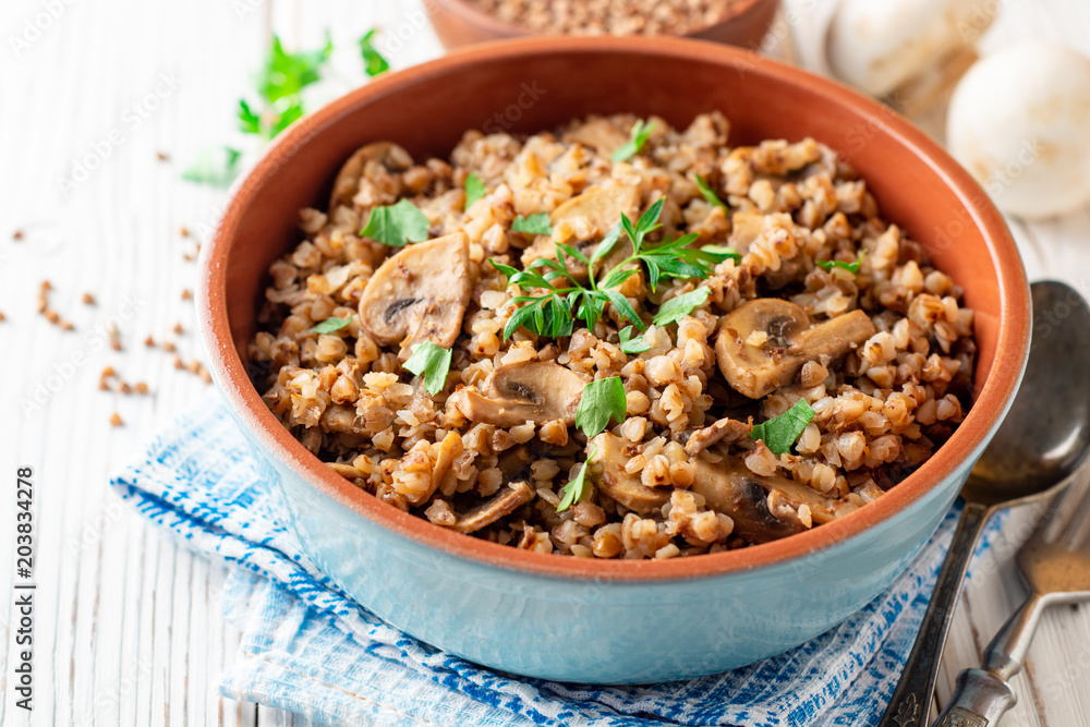 Buckwheat porridge with mushrooms in a bowl on white wooden background Buckwheat porridge with mushrooms in a bowl on white wooden background