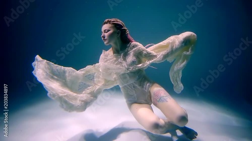 Wallpaper Mural a young woman with a tattoo on her leg is under water, she looks like a sea siren with dreadmills on the left Torontodigital.ca