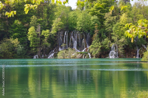 Fototapeta Naklejka Na Ścianę i Meble -  Piękny pejzaż szmaragdowego jeziora w Plitwickim Parku Narodowym w Chorwacji, wodospady, porośnięte bujną zielenią wzgórze 