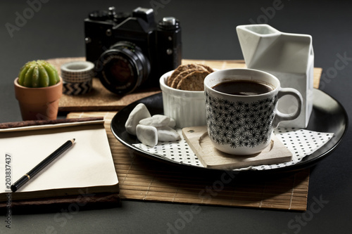 BlaTable set with coffee,  camera and note pad with empty space fot writing