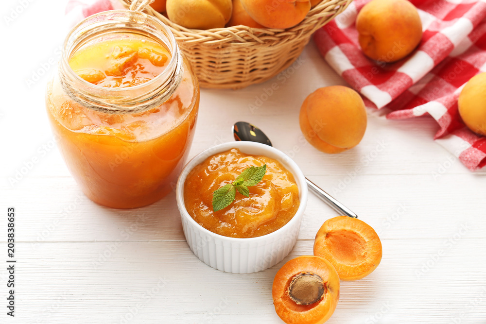 Apricot jam in bowl and glass jar on white wooden table Apricot jam in bowl and glass jar on white wooden table