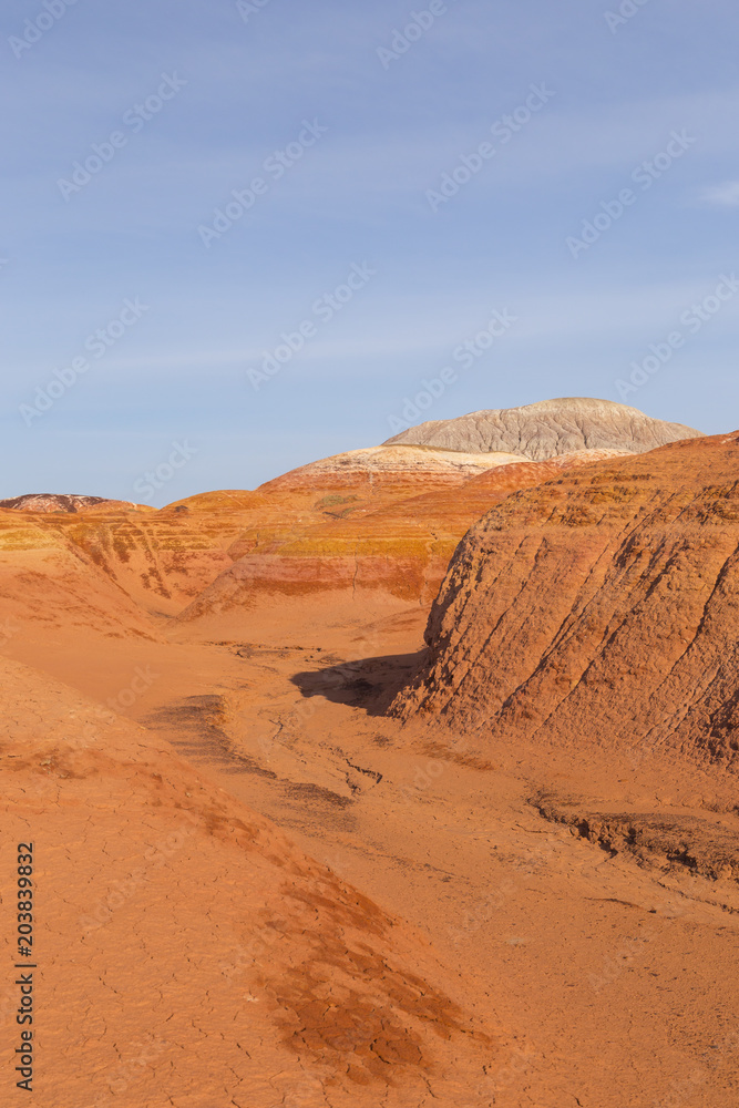 Fototapeta premium Multicolored red, orange and yellow striped hills under a bright blue sky in Eastern Kazakhstan