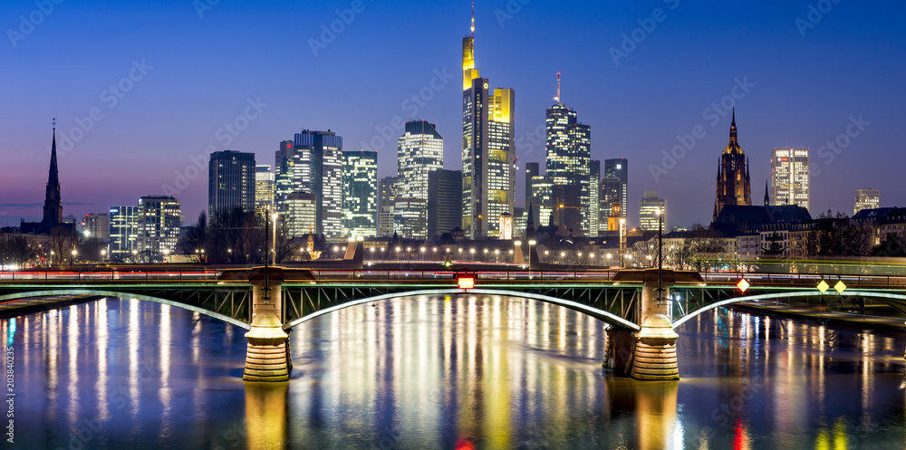 Fototapeta premium Metropolia bankowa Frankfurt nad Menem widziana z Flößerbrücke wieczorem z rzeką Men na pierwszym planie