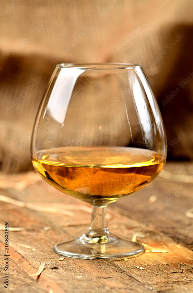 Glass of cognac on rustical wooden background Glass of cognac on rustical wooden background