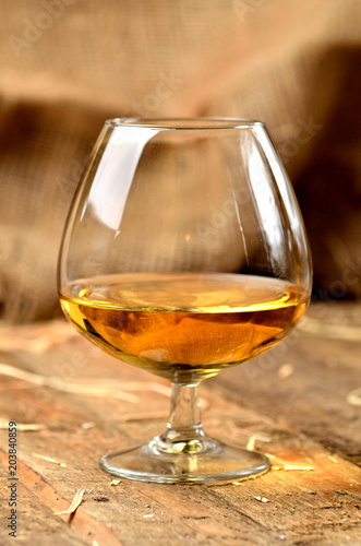 Glass of cognac on rustical wooden background