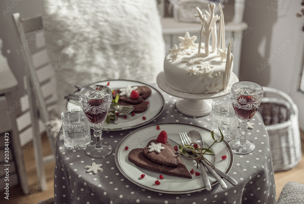 Table for two with white cake, chocolate biscuits and red wine