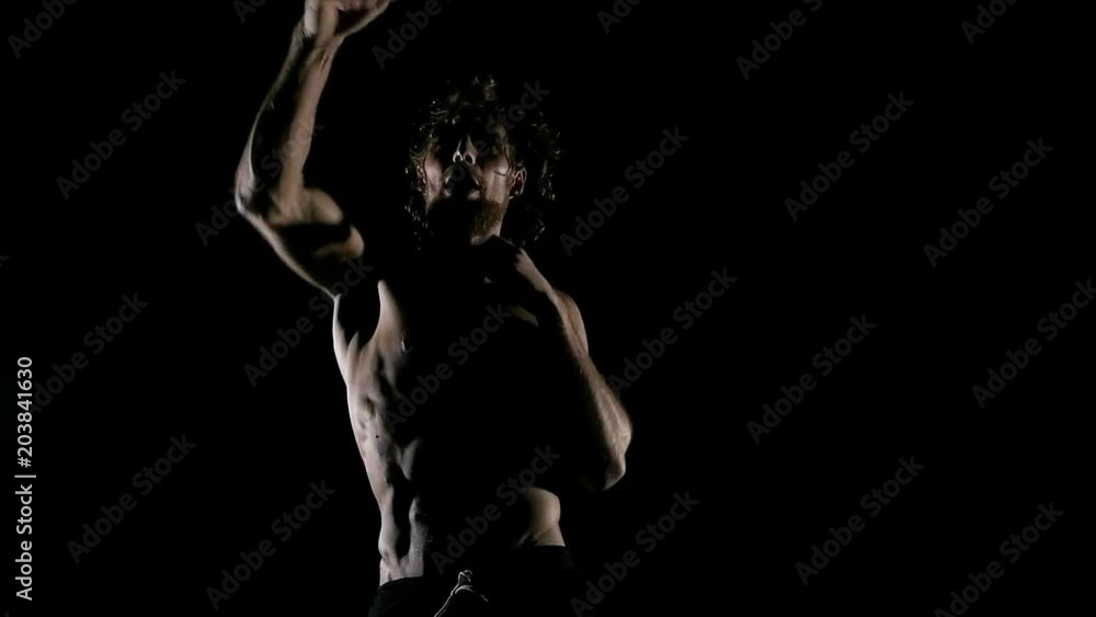 Slow motion of man shadow boxing in black background. Young white man with six packs.. Fighting sprit concept. Slow motion of man shadow boxing in black background. Young white man with six packs.. Fighting sprit concept.