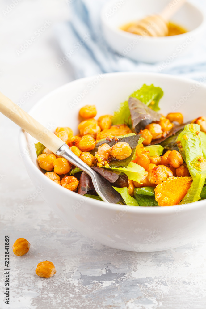 Salad with baked pumpkin and chickpeas with mustard-honey dressing in a white plate, macro. Healthy vegan food concept. Salad with baked pumpkin and chickpeas with mustard-honey dressing in a white plate, macro. Healthy vegan food concept.