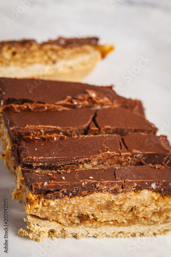 Coconut-oat raw vegan sliced cake with chocolate. Top view, light background, copy space. Healthy vegan food concept.