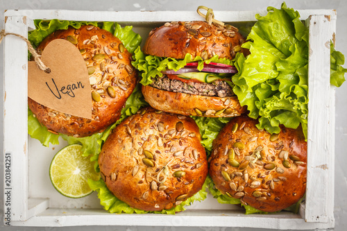 Vegan bean burger with vegetables and tomato sauce in a white wooden box, top view. Healthy vegan food concept. © vaaseenaa