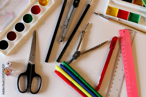 School supplies on the white background: watercolor, pencils and brushes. School and education. Colorful accessories. Preparation for school. Art composition. Drawing and painting.