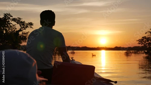Man on boat in amazon lake at sunset photo
