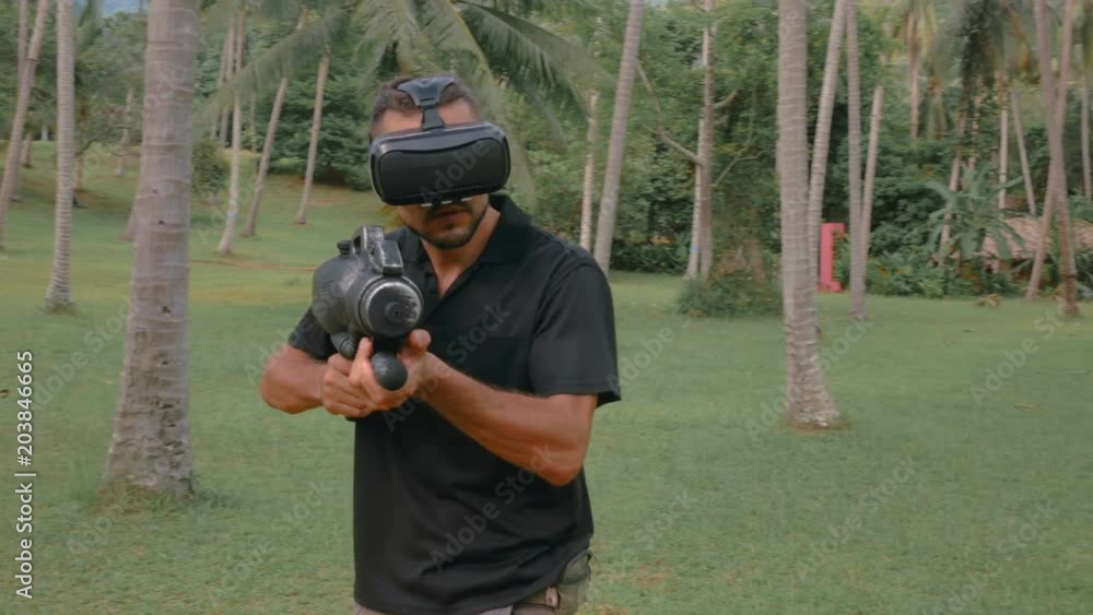 Man with weapon playing virtual reality game in the jungle Man with weapon playing virtual reality game in the jungle