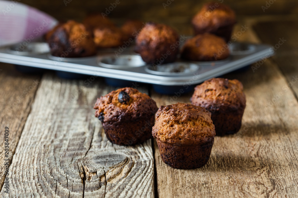 Burnt muffins in baking pan on rustic wooden table Burnt muffins in baking pan on rustic wooden table