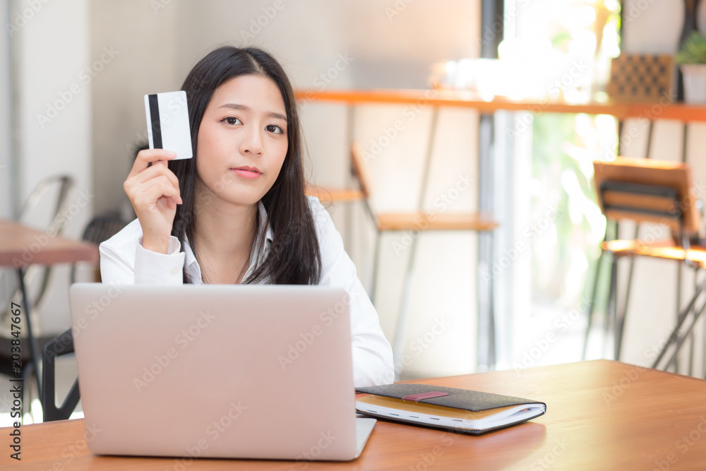 Beautiful young asian woman holding a credit card and shopping online with using laptop computer at cafe, girl payment on notebook to internet, business ecommerce and lifestyle concept. Beautiful young asian woman holding a credit card and shopping online with using laptop computer at cafe, girl payment on notebook to internet, business ecommerce and lifestyle concept.