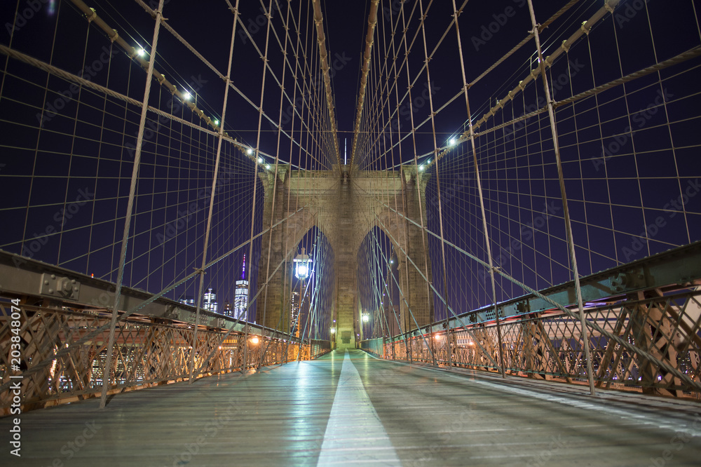Fototapeta premium New York City Brooklyn Bridge in Manhattan. Closeup with skyscrapers and city skyline over Hudson River at night.