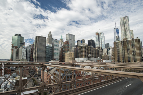 Manhattan skyline seen from the beautiful Brooklyn bridge. Cloudy day in New York City, USA.