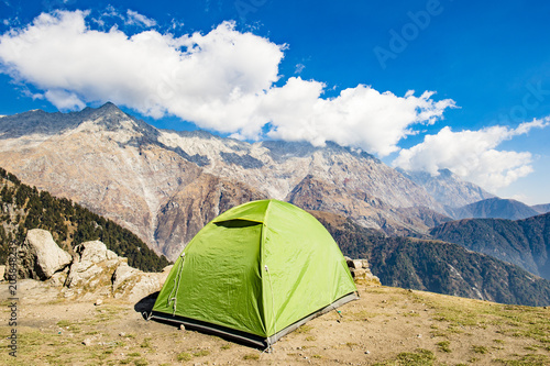 A single green tent seen against Dhaulahaar peaks of Himalayas in Triund. Sunny day whit some clouds. Dharamshala  Himachal Pradesh. India