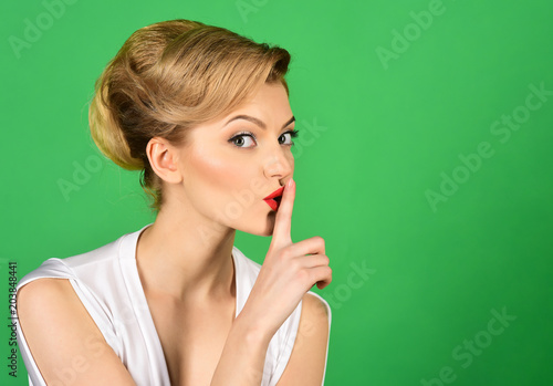 Hush. Charming woman having secret holds finger on lips, shows shh sign. Attractive woman in white dress, retro hairdo making gesture silence. Discount, sale, season sales. Copy space for advertise.