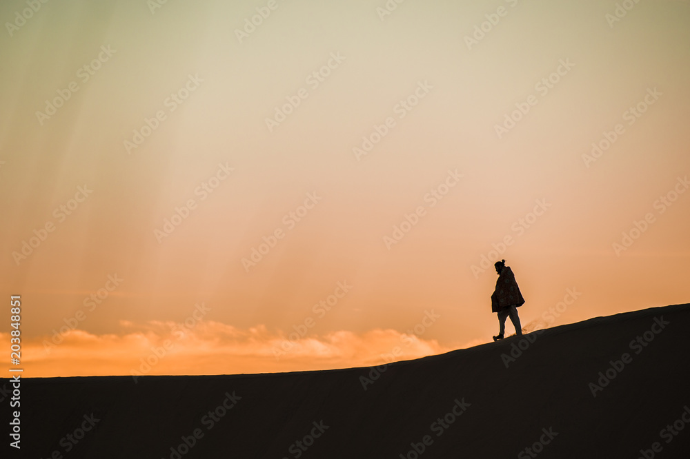 Man walk on a desert sand dunes at sunset in Rajasthan, India.