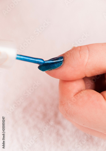 Detail of applying dark blue nail polis on the thumb