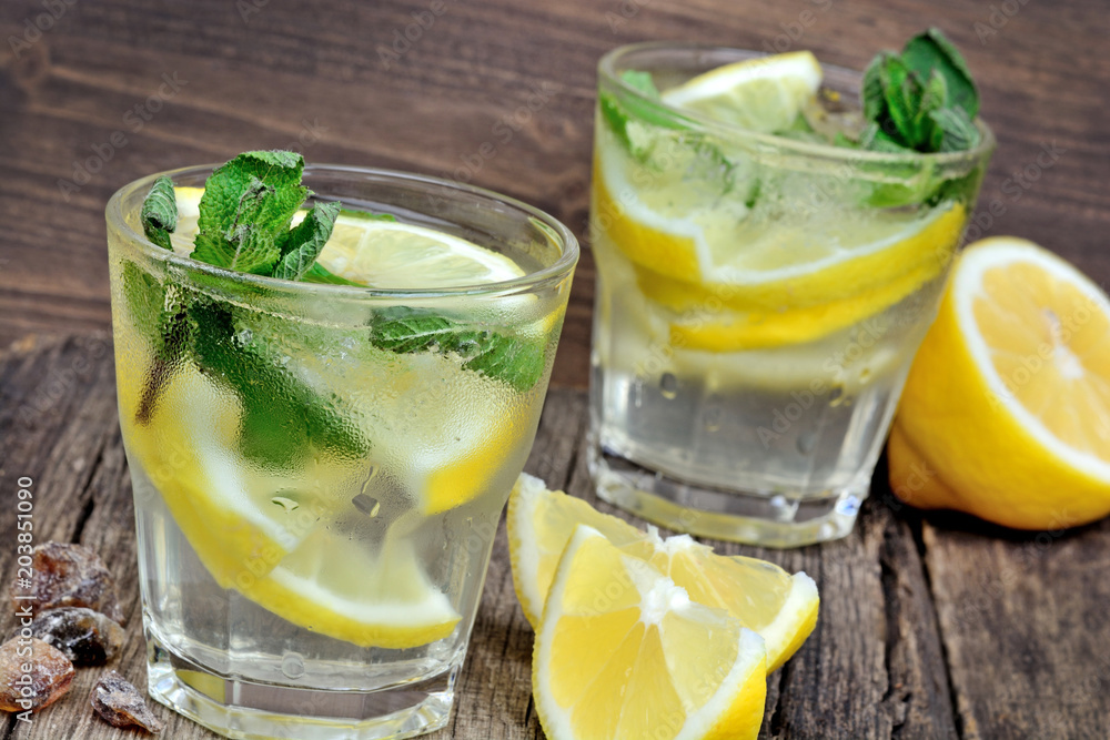 Water with fresh lemon and mint on wood background Water with fresh lemon and mint on wood background