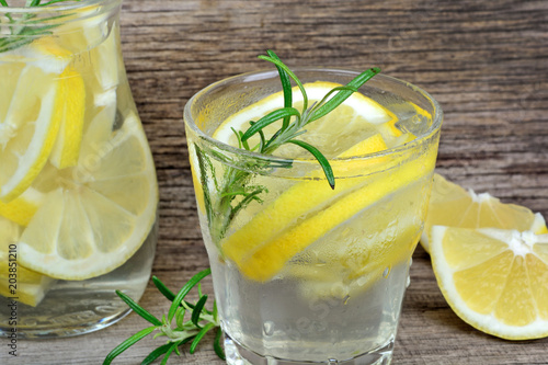 Lemon detox water with rosemary in a glasses on wood table