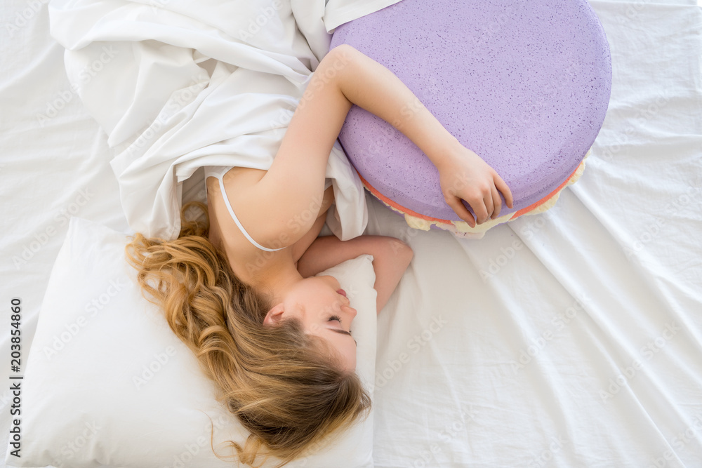 top view of blonde woman sleeping with big purple macaron on bed top view of blonde woman sleeping with big purple macaron on bed