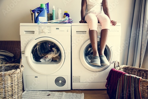 Fényképezés Young teen girl waiting for clothe to be washed from washing machine