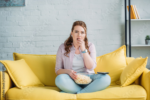 beautiful woman watching movie and eating popcorn at home