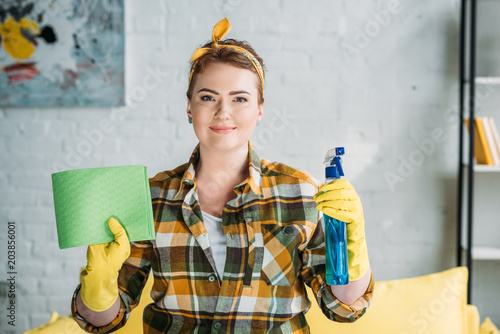 beautiful woman holding rag and spray bottle for cleaning at home